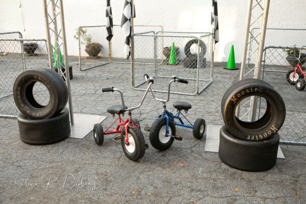 A pair of tricycles are parked next to a set of tires.